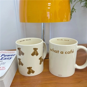 Close-up of cream ceramic teddy bear mugs on a wooden desk with a cozy home atmosphere