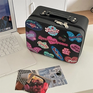 Close-up of black PU leather vanity case with colorful retro stickers on white desk
