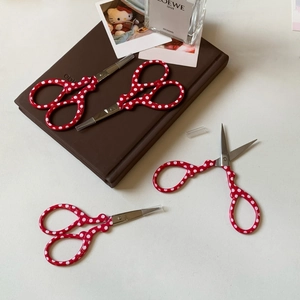 Close-up of red polka dot stainless steel scissors with transparent safety covers