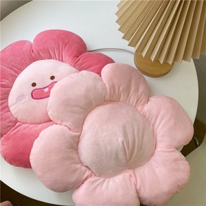 Close-up of soft pink flower plush pillows with cute embroidered facial expressions