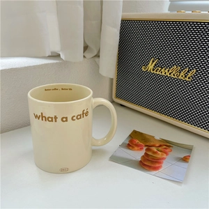 Cream ceramic teddy bear mug with coffee slogans on a bright minimalist tabletop