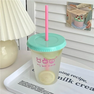 Close-up of matte plastic coffee cup featuring cartoon cats and a green lid with straw