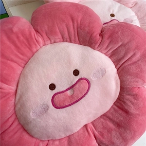 Close-up of pink plush flower cushion with cute embroidered smiling face detail