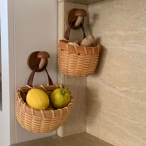 Close-up of woven ginger storage baskets with leather straps hanging on mushroom hooks