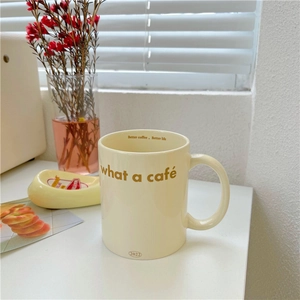 Detailed view of cream ceramic mug with what a café text and better coffee life slogan