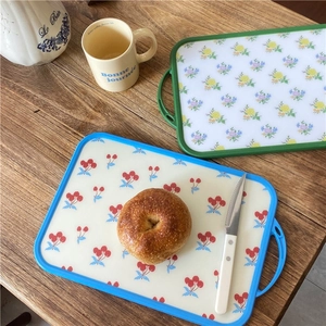Detail of vintage floral and cherry print cutting boards with handle on wooden table