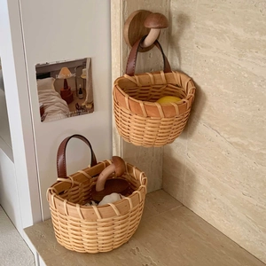 Detail of woven baskets with leather handles and wooden mushroom wall hooks