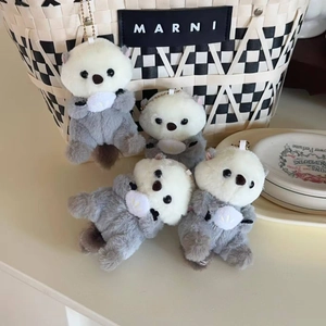 Close-up of four cute plush sea otter keychains with soft fur and metal bead chains