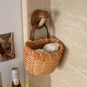 Close-up of hand-woven storage basket with leather handle and wooden mushroom hook