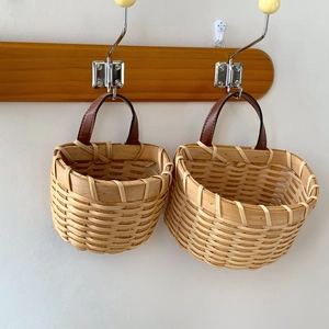 Close-up of handmade wall-hanging woven baskets with natural wood finish and leather handles