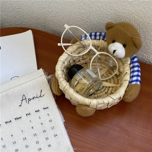 Detail of handmade woven bear storage basket holding glasses and perfume on desk