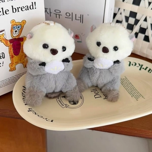 Close-up of plush sea otter charms with metal chains in a decorative dish