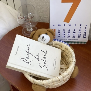 Detail of handmade straw basket with plush bear decor on dark wooden desk surface