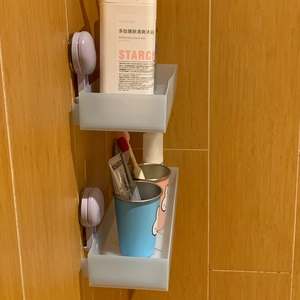 Detail of suction-mounted bathroom shelves in semi-transparent grey-blue plastic