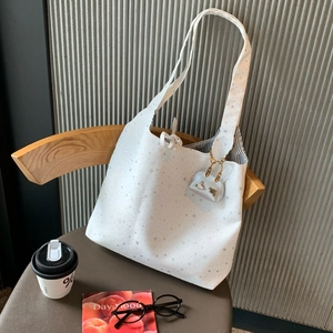 Detail of white tote bag featuring star patterns and Saturn logo charm on a vintage chair