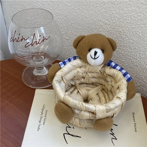 Detail showing a woven bear storage basket with a blue plaid shirt on white books