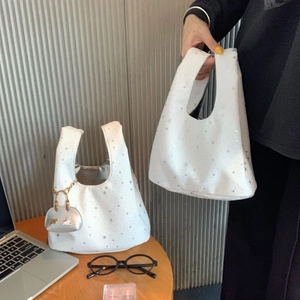 Detail of white star print handbag with heart-shaped charm and metallic chain accessory