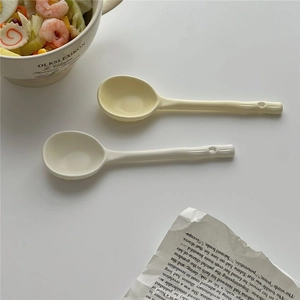 Irregular handmade ceramic soup spoons in creamy yellow and beige with hanging holes