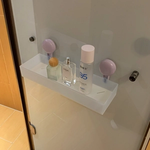 Detail of white frosted bathroom shelf showing strong purple suction cup wall mounting