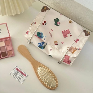 Flat lay of a cute cartoon bear makeup bag with brushes and soft lifestyle props
