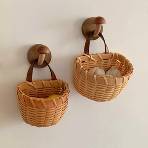 Detail of hand-woven storage baskets with leather handles and mushroom wooden hooks on wall