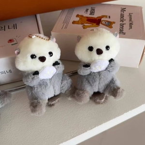 Detail of cute plush sea otter charms with soft fur, shells, and gold chains for backpacks