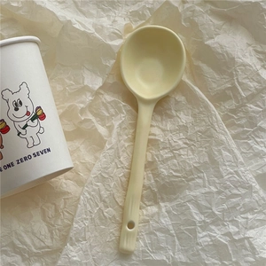 Macro shot of minimalist cream-colored ceramic spoon with matte finish and hanging hole