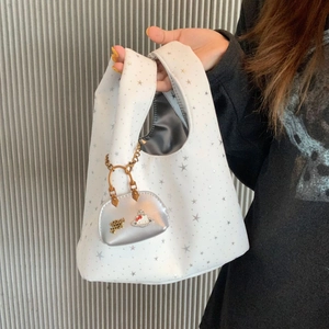 Close-up of white star print tote bag with metallic lining and silver charm accessory