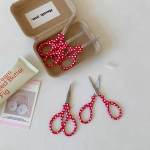 Macro view of red polka dot mini stainless steel scissors with protective blade covers