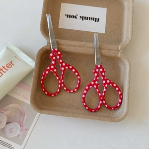 Detail of red polka dot stainless steel scissors with protective caps in eco-packaging
