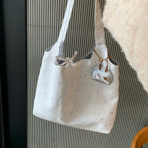 Close-up of star pattern canvas tote bag with striped lining and cute silver kitty charm