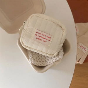 Quilted beige cosmetic bag with pink label in a cozy gift box presentation