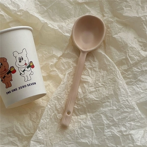 Detail of cream ceramic spoon featuring anti-slip handle with a convenient hanging hole