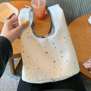 Detailed view of white canvas tote bag with silver star patterns held by hand