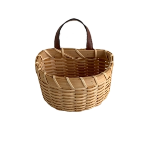 Handwoven bamboo storage basket with brown leather handle in a minimalist Nordic style
