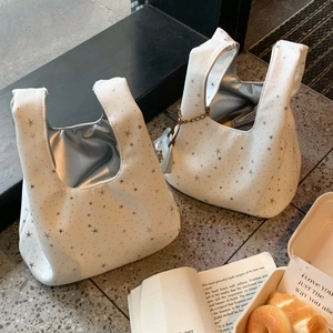 Chic white wrist bags with silver stars and metallic lining on terrazzo floor
