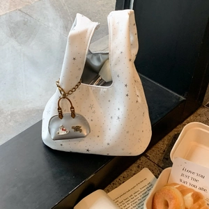 Detail of white star pattern handbag with silver charm on urban background