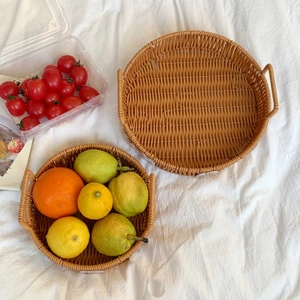 Close-up of woven rattan-style storage basket with handles for organizing fruit and snacks