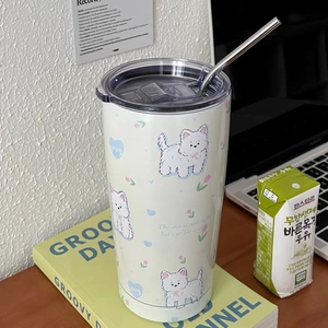 Detail of cream-colored insulated dog cup with stainless steel straw on a cozy desk