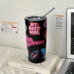 Detail of black stainless steel straw cup with colorful stickers on a desk setting