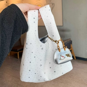 Detail shot of canvas tote bag with star patterns and a silver charm bag accessory