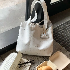 Close-up of white canvas tote bag featuring star pattern, striped lining and mini charm