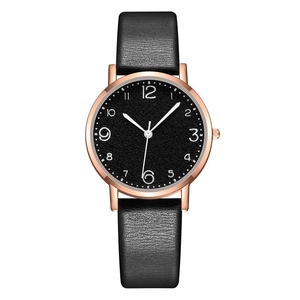 Close-up of leather strap watch with rose gold case and black Arabic numeral dial
