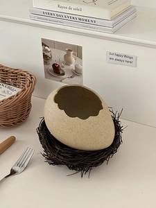 Detail of egg-shaped ceramic dessert bowl with a natural bird nest base in cream white