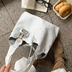 White canvas tote bag with star print and cloud charm in a flat lay lifestyle view
