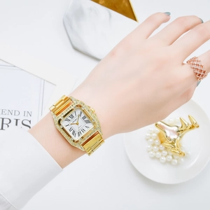 Dettaglio di un orologio di lusso in acciaio dorato con strass e numeri romani sul polso donna