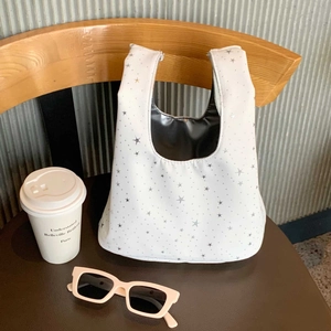 Detail of white tote bag with silver star pattern on a leather chair in urban cafe