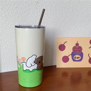 Detailed view of cream-colored puppy print insulated tumbler with a straw on a wooden table