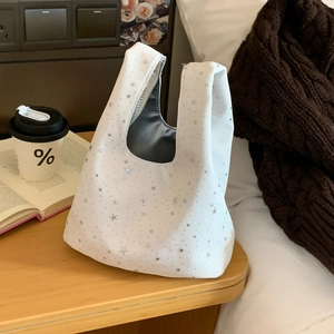 Close-up of a white tote bag with silver star patterns on a cozy wooden table background
