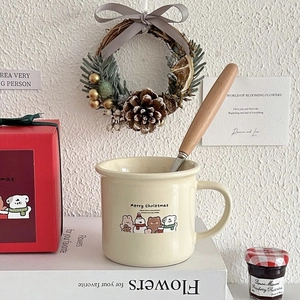 Close-up of Christmas ceramic mug with cartoon bear, wooden spoon and festive decorations